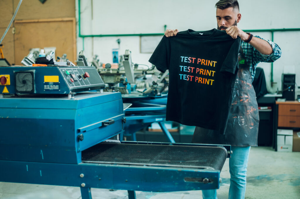 A worker uses a drying oven for a test print T-shirt.