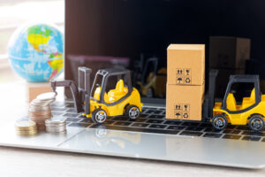 Fast turnaround custom printing concept: mini forklifts carry cardboard boxes and quarters across a laptop.