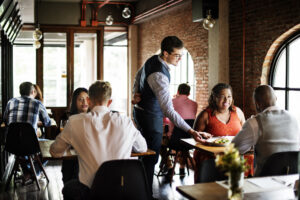 A server brings food to a table in a busy restaurant.